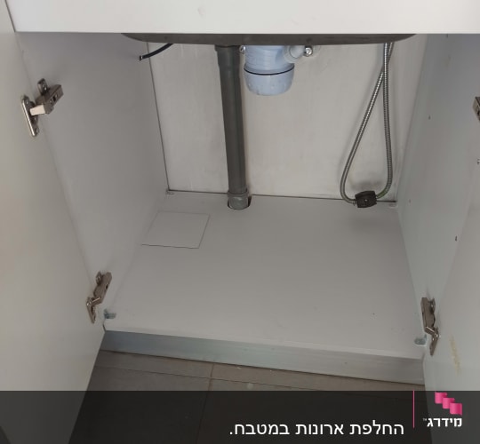 ארון מטבח פתוח עם צנרת כיור וניקוז